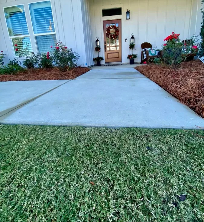 Beautifully maintained lawn and pathway leading to a home entrance in Panama City, FL, showcasing professional lawn care services.